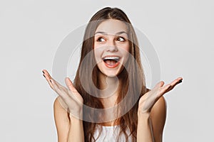 Surprised happy beautiful woman looking sideways in excitement on gray background