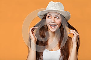 Surprised happy beautiful woman looking sideways in excitement, isolated on orange background photo