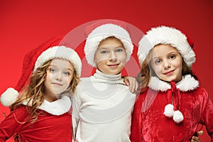 The happy boy and girls in santa claus hats with gift boxes at studio