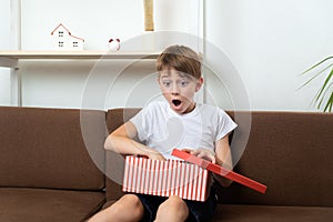 Surprised happy boy opened gift. Child with gift box with an open box in his hands