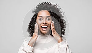 Surprised happy girl portrait. Emotional african american woman with hands near face talking