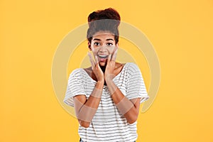 Surprised happy lady with curly hair holding her face and looking camera isolated