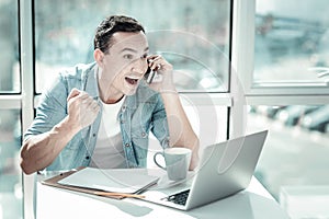 Surprised happy man having phone conversation and smiling.