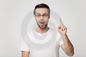 Surprised happy millennial man rising finger up on empty copyspace.
