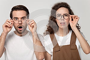 Surprised happy millennial man and woman looking closely at camera.