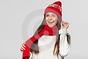 Surprised happy woman in excitement. Christmas girl wearing knitted warm hat and scarf, isolated on gray background