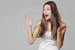 Surprised happy woman looking sideways in excitement, isolated on gray background