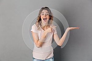Surprised happy woman in t-shirt holding copyspace on the palm