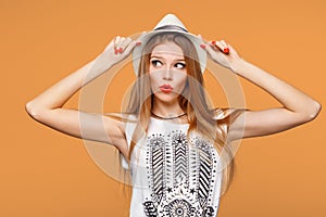 Surprised happy young woman looking sideways in excitement. Isolated over orange background