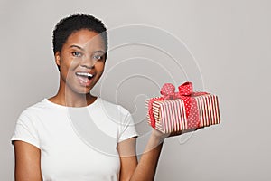 Surprised healthy woman holds colorful gift present box on white background. Celebration and holiday concept