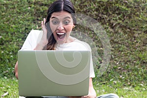 Surprised Hispanic woman using laptop in outdoors