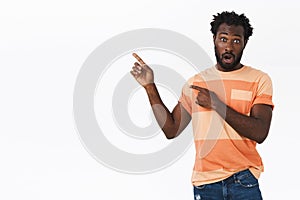 Surprised and impressed african american bearded guy in striped t-shirt, open mouth fascinated, gasping shocked as