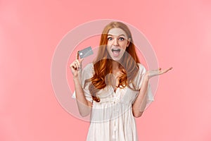 Surprised and impressed cute happy, cheerful redhead girl amazed she got awesome bonuses on bank account, using credit