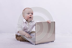 Surprised infant businessman with laptop. Cute toddler boy playing with notebook. Idea for extreme degree of surprise