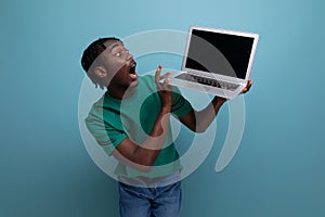 surprised joyful african young brunette male consultant in casual t-shirt with open laptop