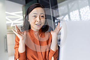 Surprised joyful and smiling woman looking at laptop screen, businesswoman using headset phone, at workplace for video