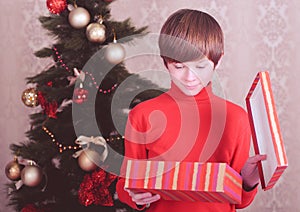 Surprised kid boy holding christmas gift in room