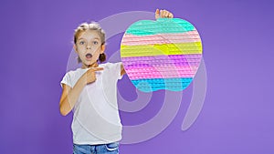 Surprised kid holding huge apple anti stress bubble. motor skills. pop it fun. child holding color popit fidget