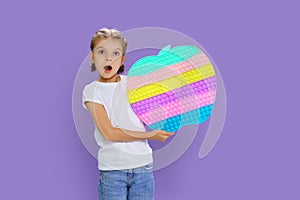 Surprised kid holding huge apple anti stress bubble. motor skills. pop it fun. child holding color popit fidget