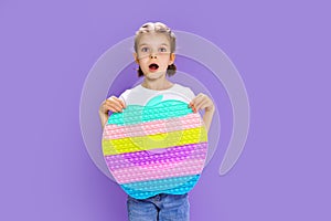 Surprised kid holding huge apple anti stress bubble. motor skills. pop it fun. child holding color popit fidget