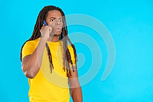 Surprised latin man with dreadlocks talking to the mobile