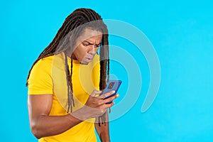 Surprised latin man with dreadlocks using a mobile phone