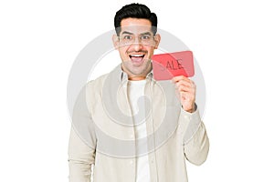 Surprised latin man holding a sale ad
