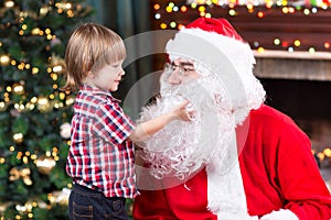 Surprised little boy looks at fake Santa Claus