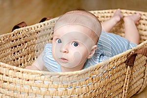 Surprised Little boy lying in wicker basket