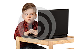 Surprised little boy working on a laptop computer