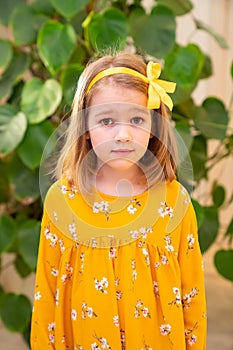 Surprised little girl,yellow dress.ribbon in hair
