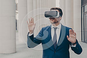 Surprised male office worker dressed formally stands outdoors in 3d goggles