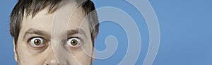 Surprised man bulging eyes on blue banner with place for text. Exophthalmos with hyperthyroidism or surprise in