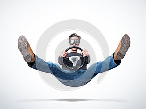 Surprised man in goggles in the air with a car steering wheel in his hands, on light background, front view. Car accident concept