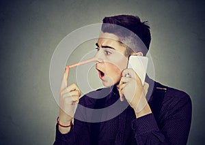 Surprised man with long nose talking on mobile phone Liar concept