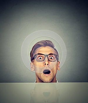 Surprised man peeking from under the table