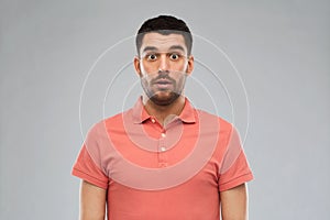 Surprised man in polo t-shirt over gray background