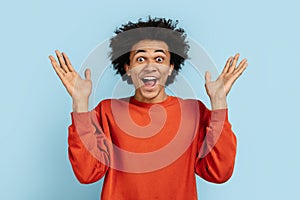 Surprised man with raised hands on blue background