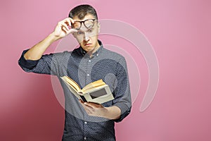 Surprised man reading a book on a pink background