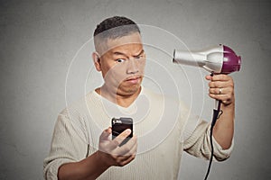 Surprised man reading social media news on phone holding hairdryer