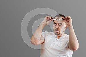 Surprised man, shocked with bulging eyes, glasses climbed his forehead, isolated on a gray background, place for printing