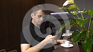 Surprised Man Sitting in Cafe with Smartphone and Reading Good Internet News