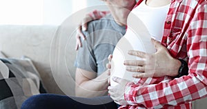 Surprised man stroking belly of pregnant wife