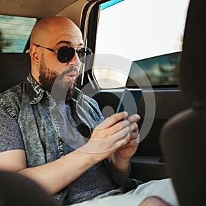 Surprised man using mobile app traveling by car