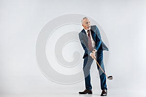 Surprised mature businessman holding golf club while playing