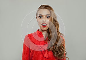 Surprised model with open mouth. Beautiful woman with makeup and long hair wearing red blouse on white background
