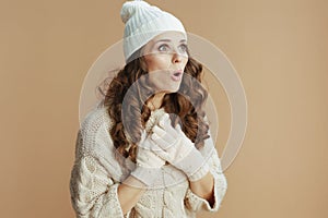 surprised modern woman in beige sweater, mittens and hat