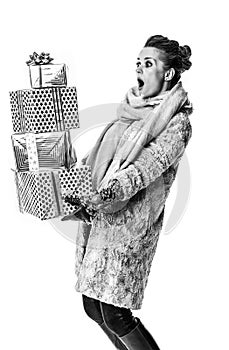 Surprised modern woman on white with pile of Christmas giftes