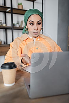 surprised muslim woman in headkerchief pointing photo