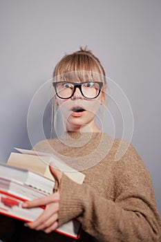 Surprised nerd caucasian student girl holding stack of books